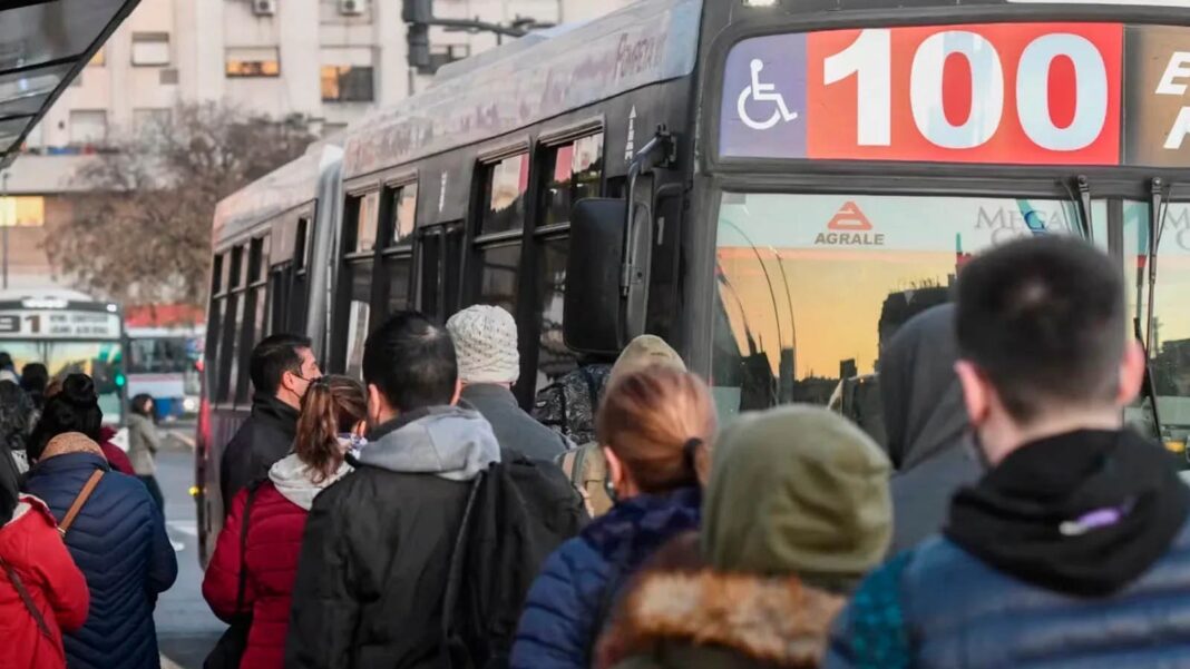 Colectivo en el AMBA con aumento de tarifas en junio de 2025. Usuarios esperan en la parada con tarjeta SUBE.