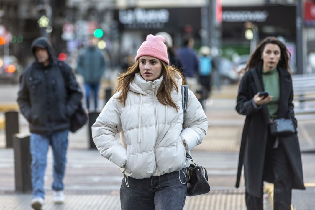 Una mujer abrigada caminando por una calle céntrica.