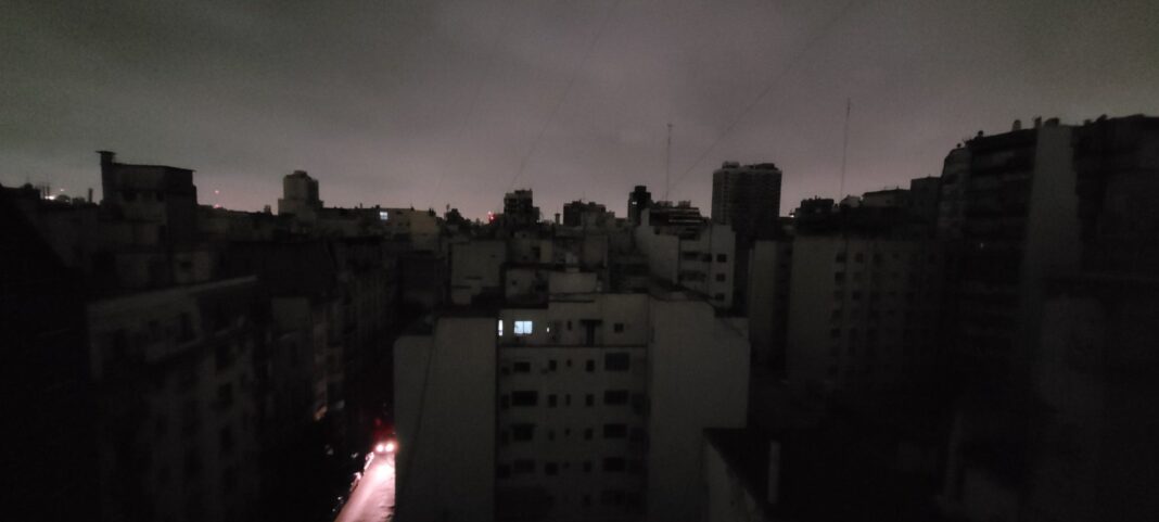 Vista nocturna del AMBA completamente a oscuras durante el apagón masivo del domingo, con edificios sin luz y cielo nublado.