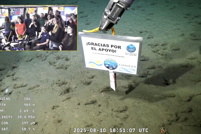 Cartel con el mensaje “Gracias por el apoyo” colocado en el fondo del mar por el CONICET durante la última inmersión del Talud Continental IV, con el equipo celebrando en pantalla dividida.