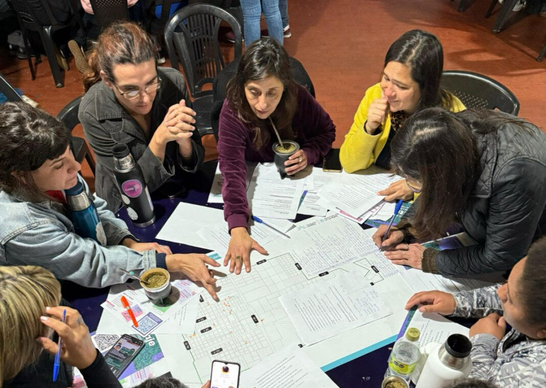 Mujeres y diversidades reunidas en un taller de género en La Plata con mapas y cuadernos sobre la mesa.